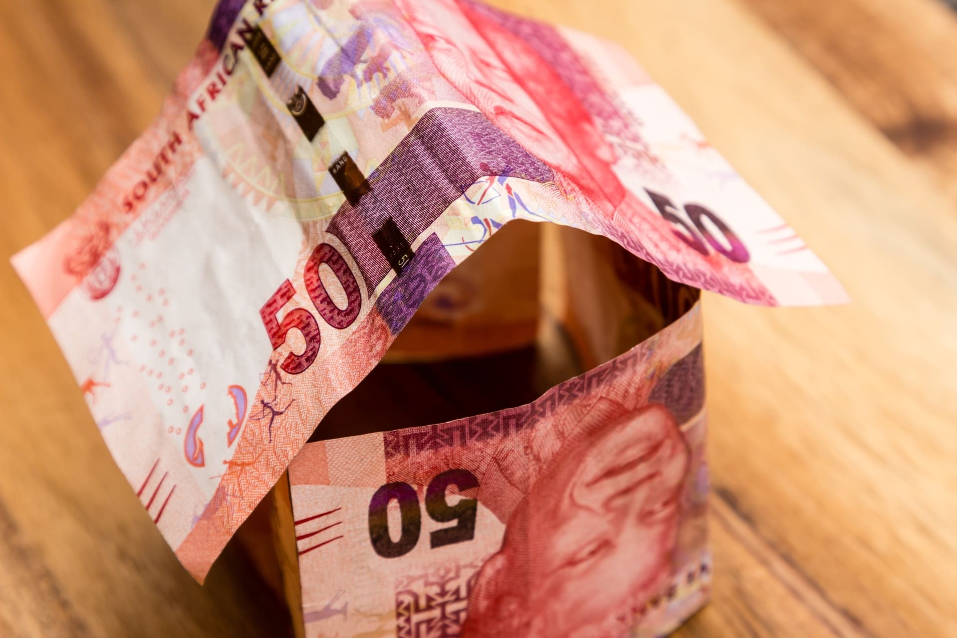 A high angle shot of some South African rand bills on a wooden surface