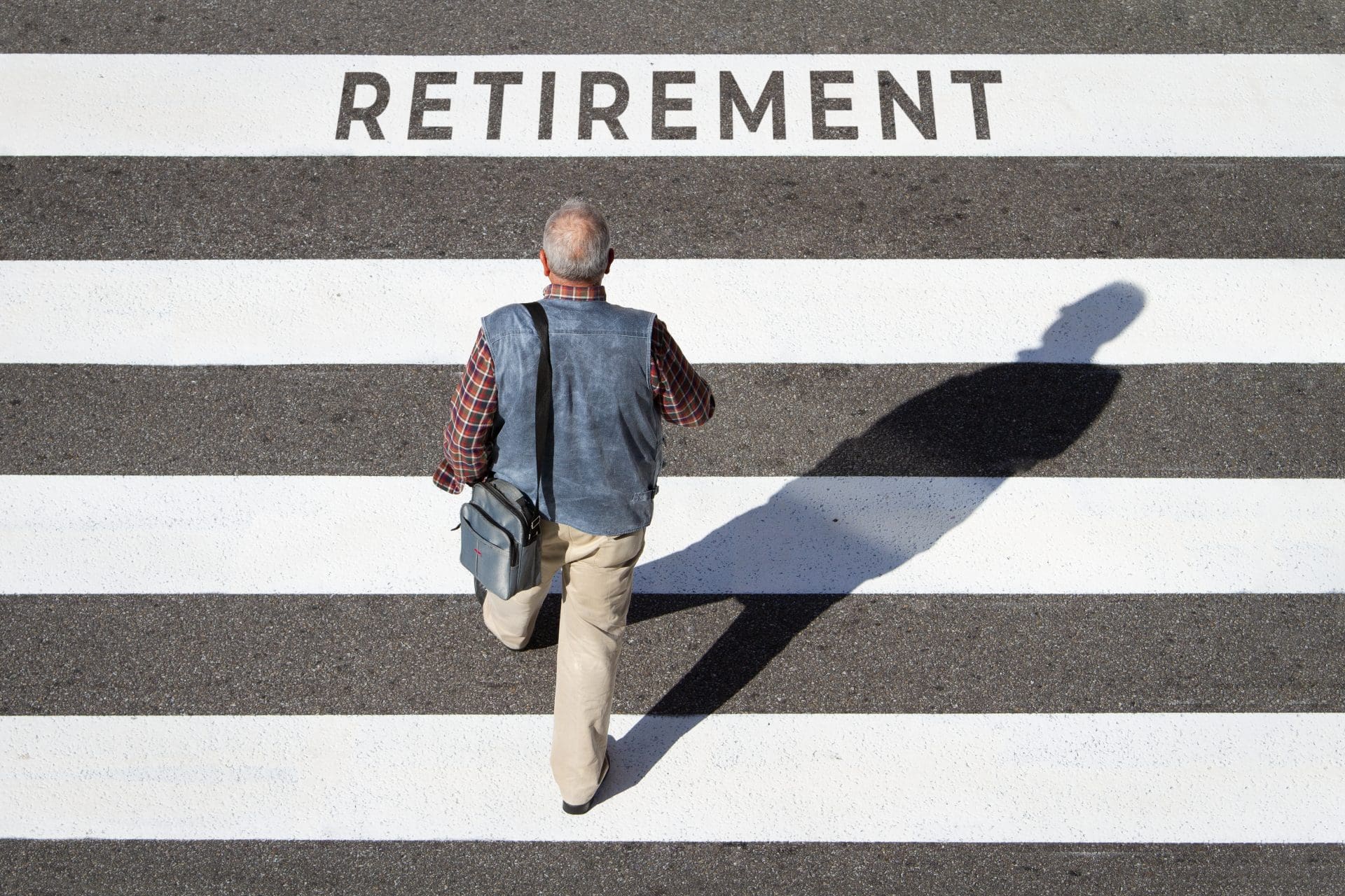 Retirement concept. Scene of a senior man walking in a cebra crossing towards retirement text. Top view